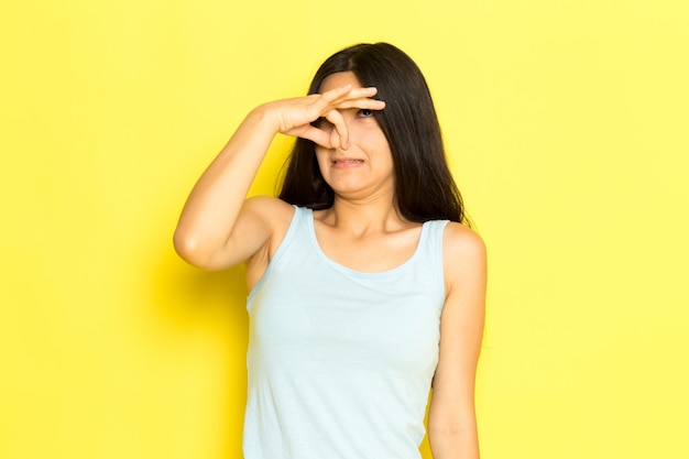 Una mujer joven de vista frontal en camisa azul posando tapándose la nariz