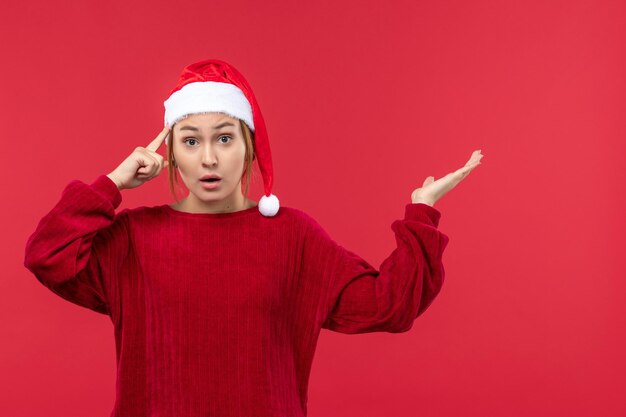 Mujer joven de vista frontal con expresión de pensamiento, Navidad roja de vacaciones