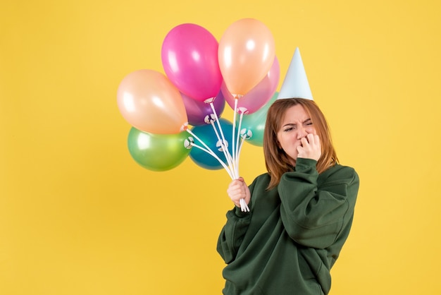 Mujer joven de vista frontal con globos de colores destacó