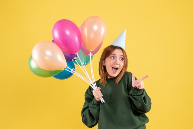 Mujer joven de vista frontal con globos de colores