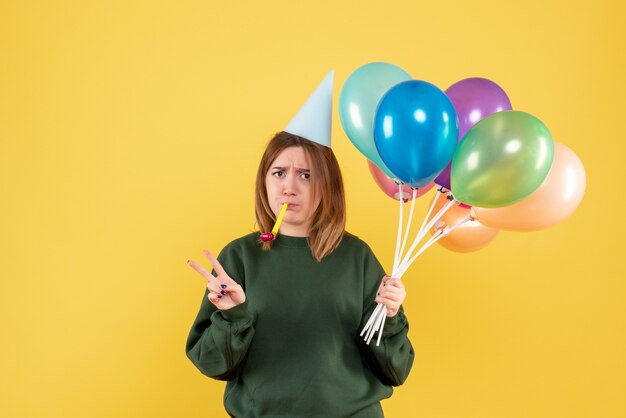 Mujer joven de vista frontal con globos de colores