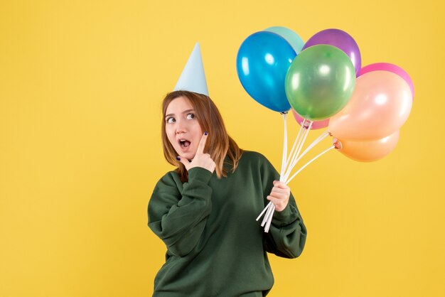 Mujer joven de vista frontal con globos de colores