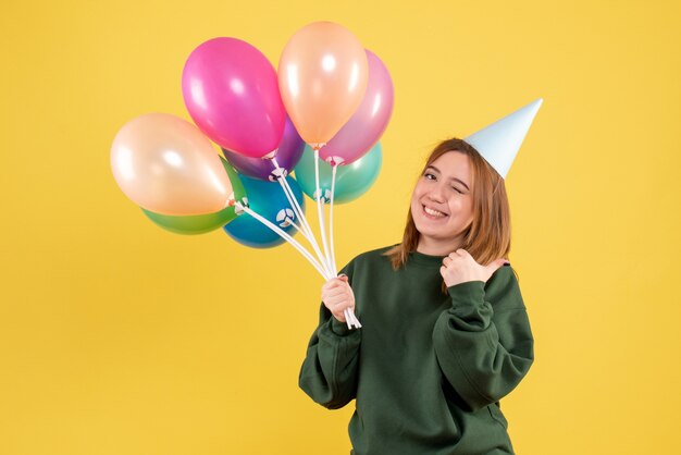 Mujer joven de vista frontal con globos de colores