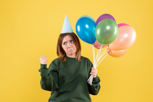 Mujer joven de vista frontal con globos de colores