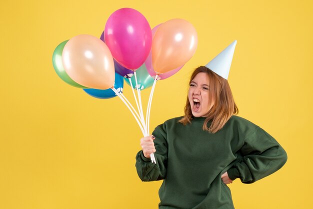 Mujer joven de vista frontal con globos de colores