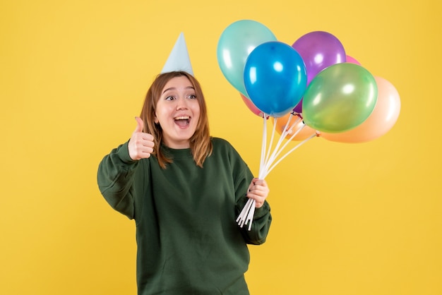 Mujer joven de vista frontal con globos de colores