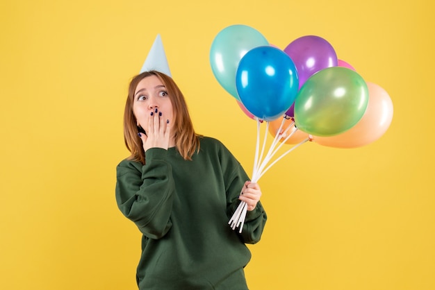 Mujer joven de vista frontal con globos de colores