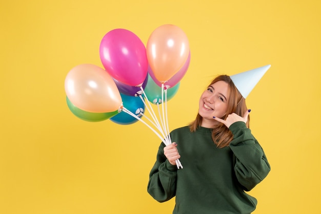 Mujer joven de vista frontal con globos de colores