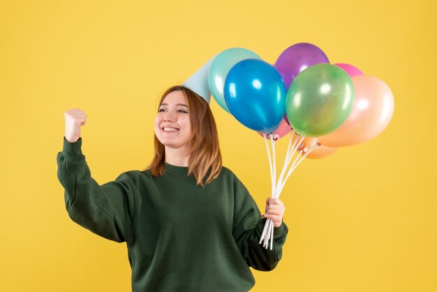 Mujer joven de vista frontal con globos de colores