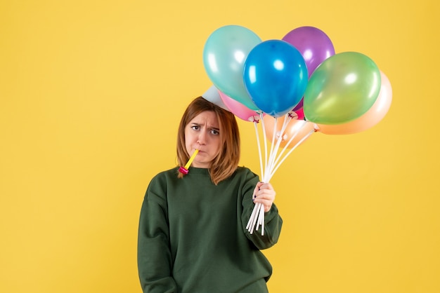 Mujer joven de vista frontal con globos de colores