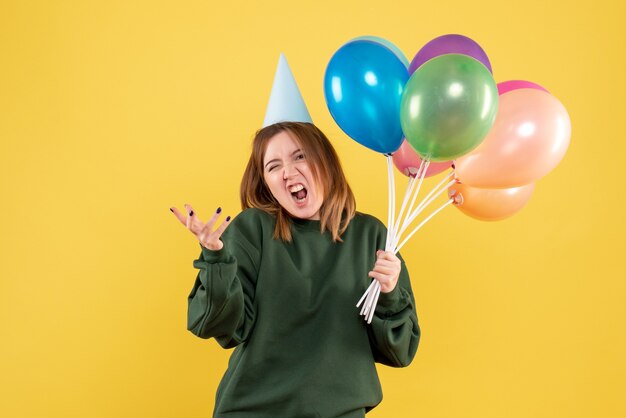 Mujer joven de vista frontal con globos de colores