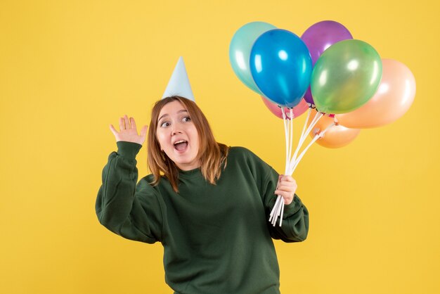 Mujer joven de vista frontal con globos de colores