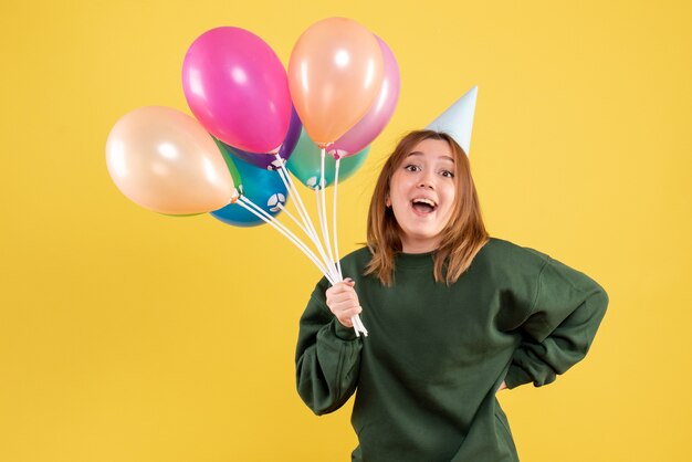 Mujer joven de vista frontal con globos de colores