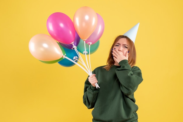 Mujer joven de vista frontal con globos de colores