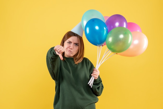 Mujer joven de vista frontal con globos de colores