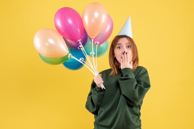 Mujer joven de vista frontal con globos de colores