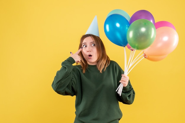 Mujer joven de vista frontal con globos de colores