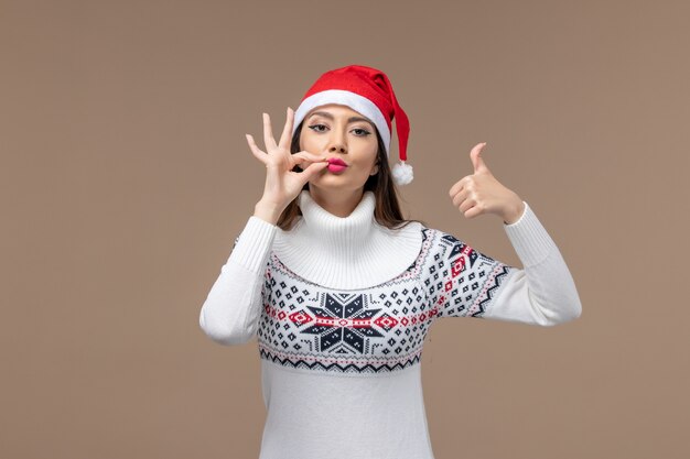 Mujer joven de vista frontal con gorro rojo de Navidad sobre fondo marrón Navidad emoción año nuevo