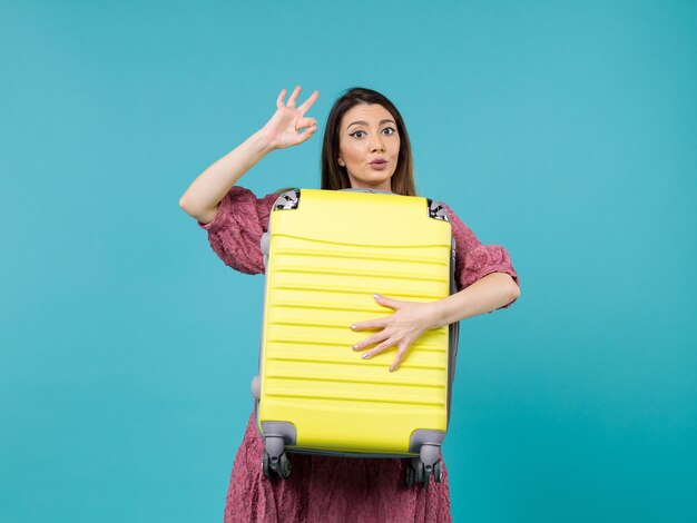 Mujer joven de vista frontal que va de vacaciones y que sostiene la bolsa grande en el escritorio azul viaje de verano viaje de vacaciones al mar