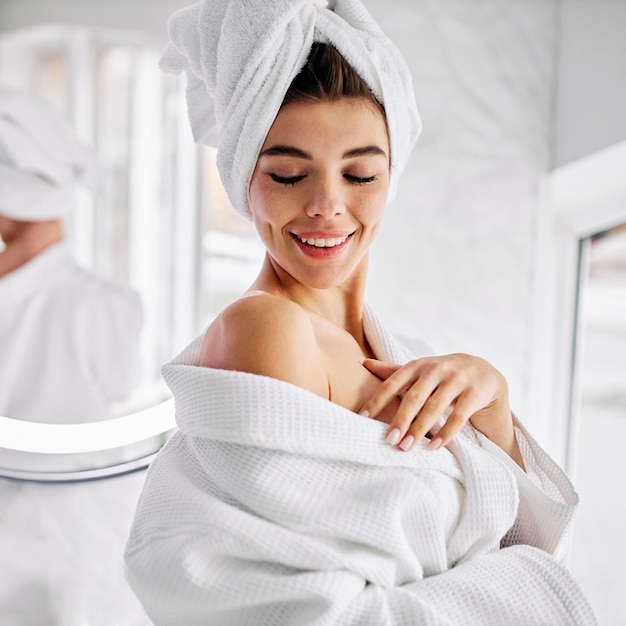 Foto gratuita mujer joven vistiendo una bata de baño y una toalla en el pelo