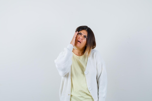 Foto gratuita mujer joven vistiendo un cárdigan blanco con dolor de cabeza