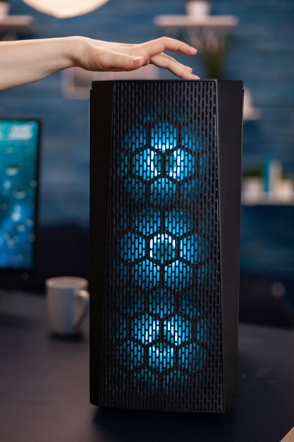 Mujer jugadora presionando el botón de inicio en la computadora RGB durante los videojuegos de space shoother durante el campeonato en línea de pie en el estudio de juegos. Sistema de PC operativo profesional para jugadores de deportes electrónicos