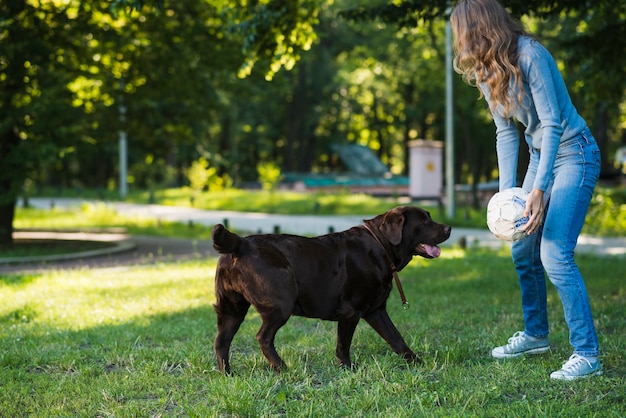 Mujer jugando al fútbol con su perro en el jardín