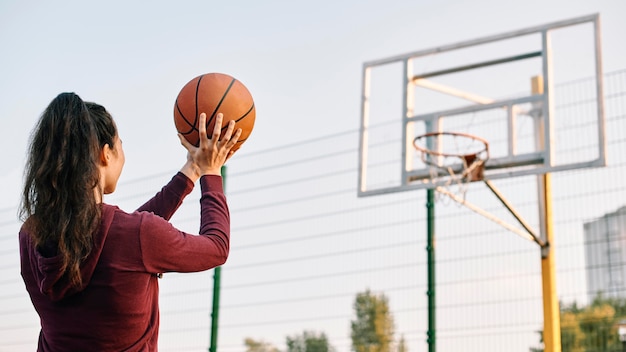 Mujer jugando baloncesto sola con espacio de copia