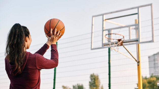 Mujer jugando baloncesto sola con espacio de copia