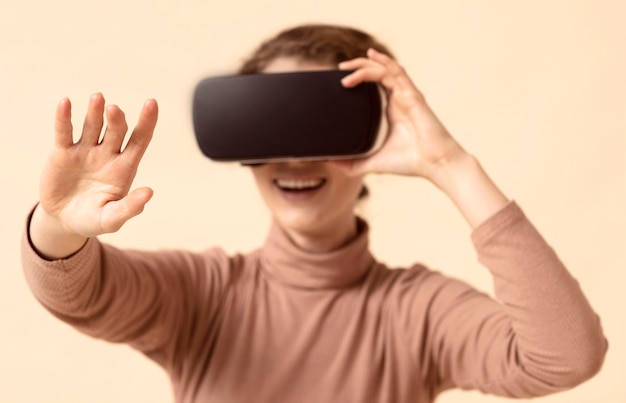 Mujer jugando con casco de realidad virtual y alcanzando su brazo