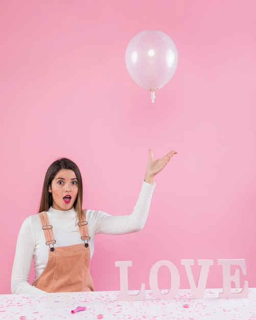 Mujer jugando con globo de aire cerca de inscripción de amor