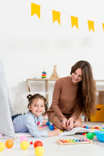 Mujer jugando con niña y juguetes en casa