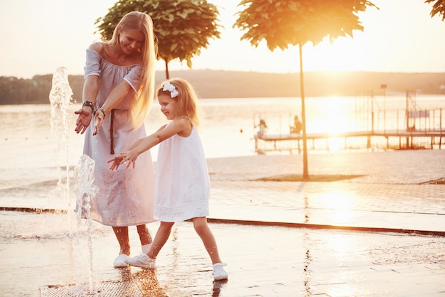 Una mujer jugando con un niño cerca del océano en el parque al atardecer