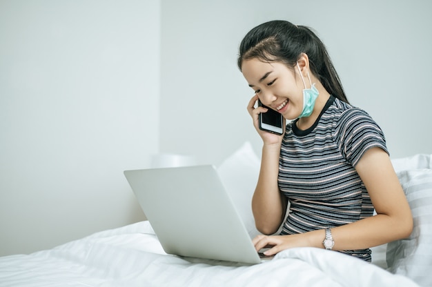 Mujer jugando portátil y hablando por teléfono.