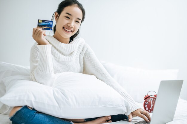 Mujer jugando portátil y mantenga una tarjeta de crédito.