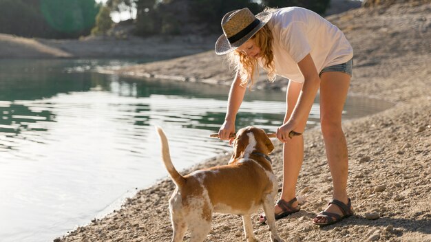 Mujer jugando con su perro junto a un lago