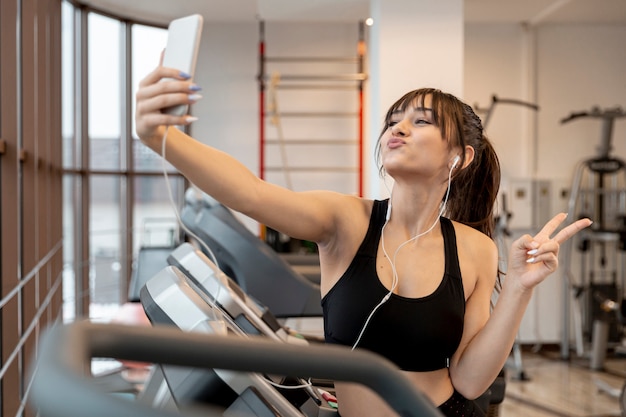 Mujer juguetona en el gimnasio tomando selfies