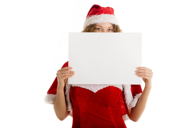 Foto gratuita mujer juguetona con gorro de papá noel mostrando un cartel en blanco