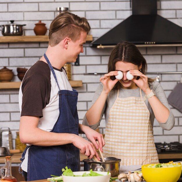 Mujer juguetona con hombre cocinando en cocina