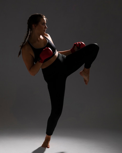 Foto gratuita mujer de karate dando una patada y fondo oscuro