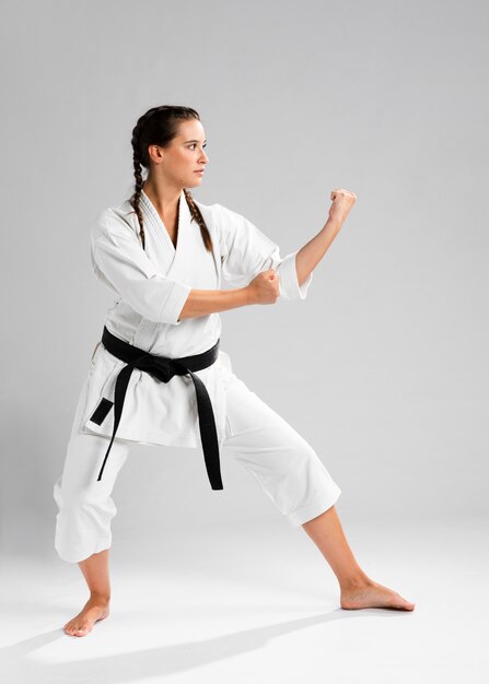 Mujer de karate de lado en kimono blanco tradicional sobre fondo blanco.