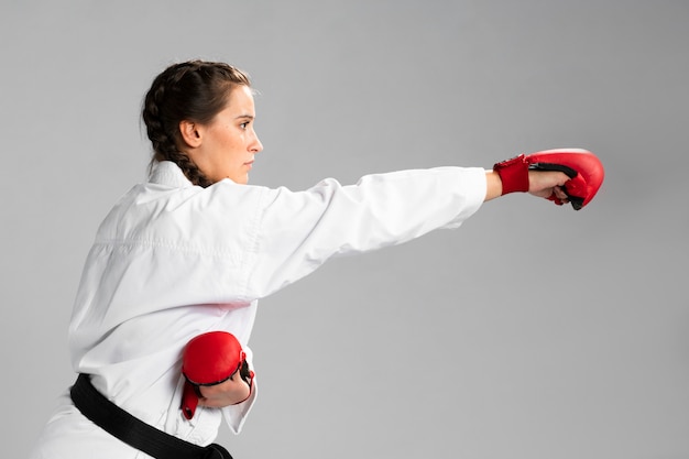 Mujer de karate de lado en kimono blanco tradicional sobre fondo blanco.