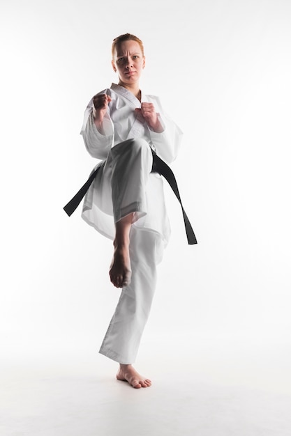 Foto gratuita mujer de karate motivada pateando vista frontal