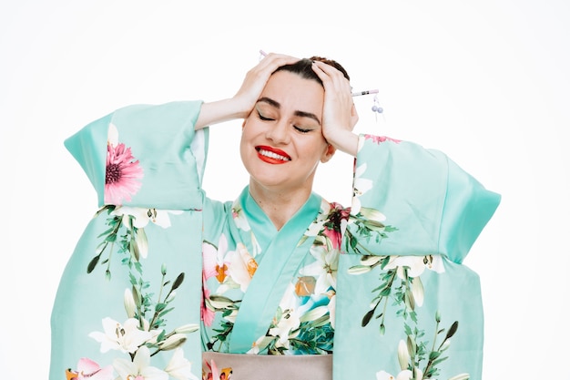 Mujer en kimono japonés tradicional feliz y complacido sintiéndose encantador tomados de la mano sobre su cabeza en blanco