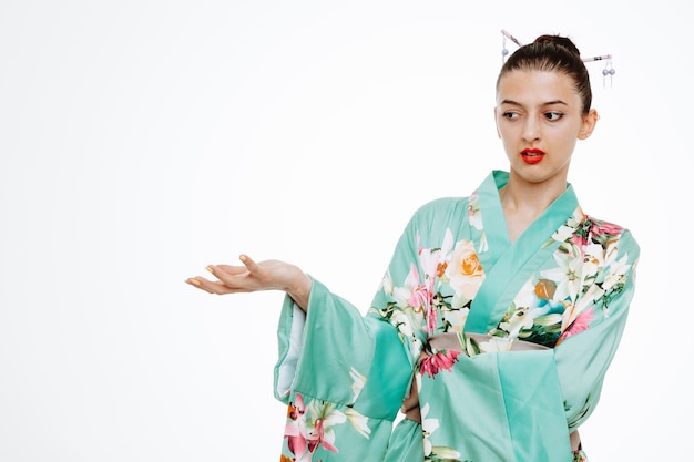 Foto gratuita mujer en kimono japonés tradicional mirando a un lado estando disgustado levantando el brazo con disgusto en blanco