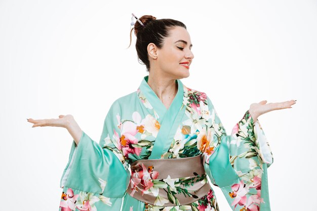 Mujer en kimono japonés tradicional mirando a un lado presentando algo con los brazos de sus manos en blanco