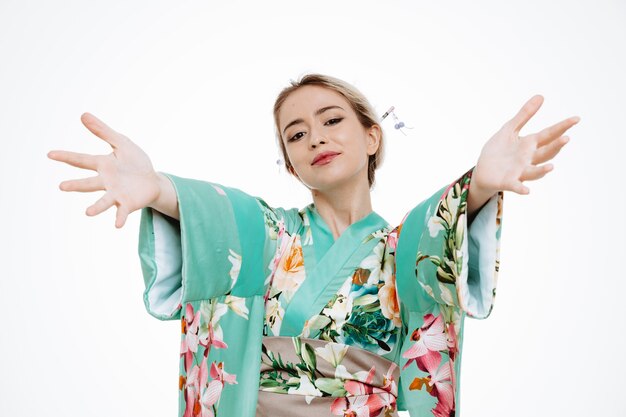 Mujer en kimono japonés tradicional sonriendo alegremente haciendo gesto de bienvenida con las manos abiertas en blanco
