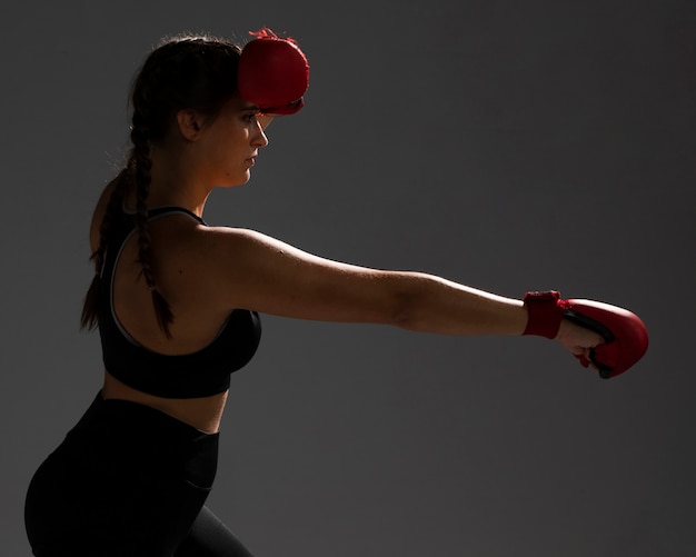 Mujer de lado golpeando con guantes de box