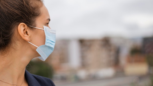 Foto gratuita mujer de lado con máscara médica con espacio de copia