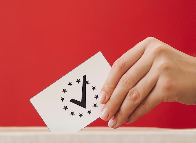 Mujer de lado poniendo una tarjeta de votación europea en una caja